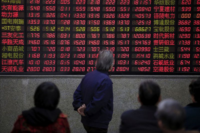 Investors look at an electronic board showing stock information at