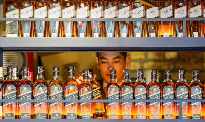 FILE PHOTO: A bartender takes a bottle of Johnnie Walker