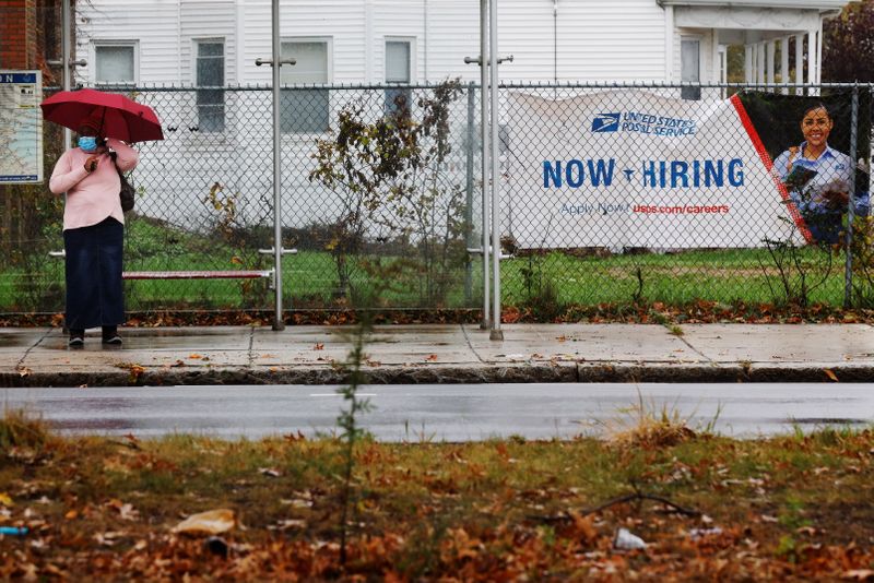 “Now Hiring” sign from the United States Postal Service hangs