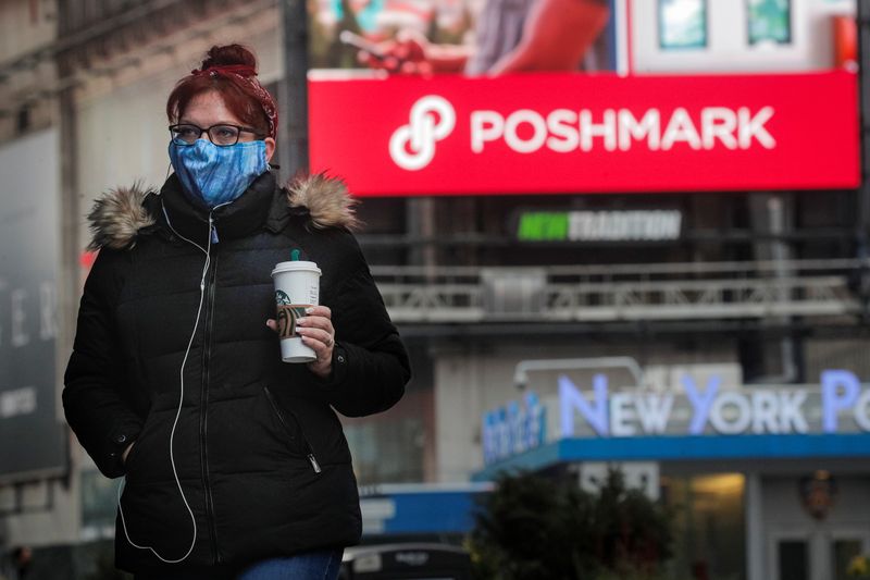 A woman walks through Times Square as a screen displays