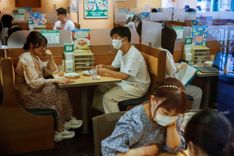 People sit in a restaurant using plexiglass separators to protect