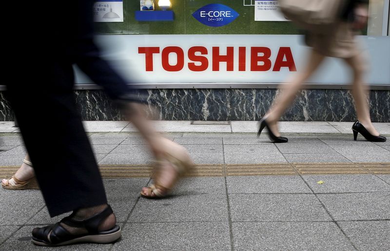 FILE PHOTO: Pedestrians walk past a logo of Toshiba Corp