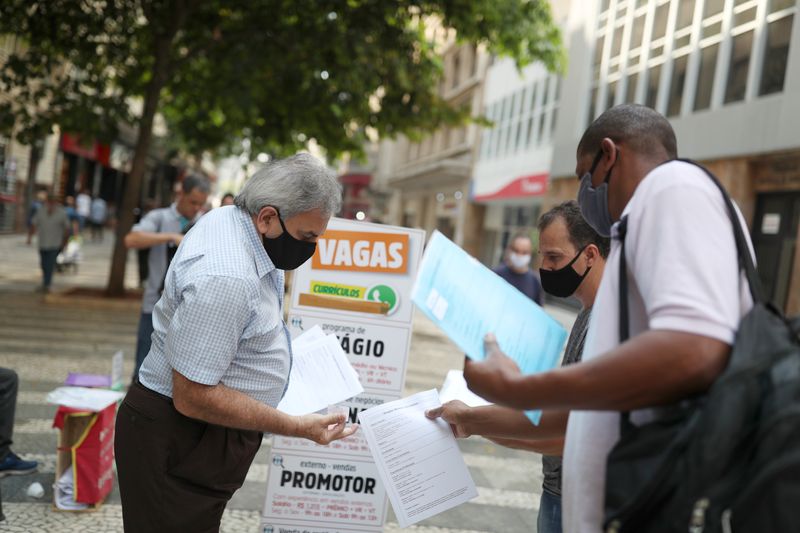 Men deliver resumes near a job listing on a board