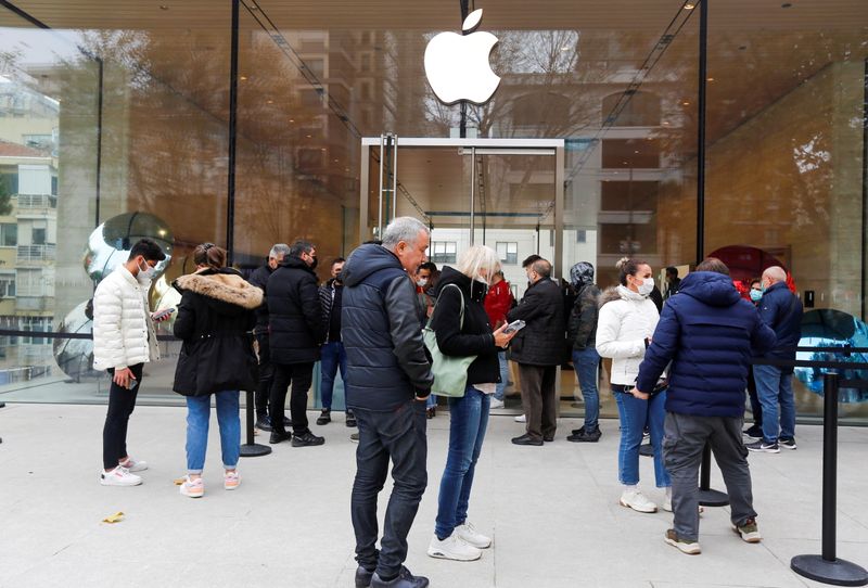 People wait in line to enter an Apple store in