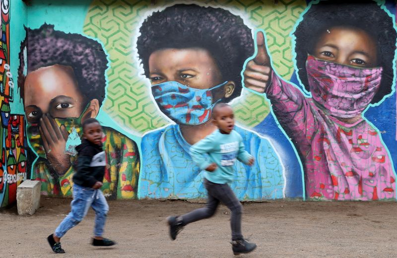 Boys run past a mural by Senzart911, of children wearing