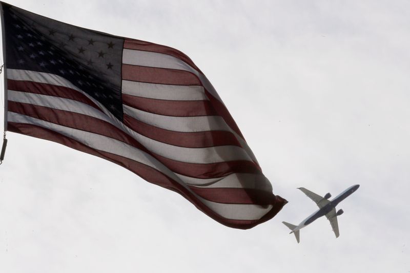 A Delta Airlines flight takes off past a U.S. flag