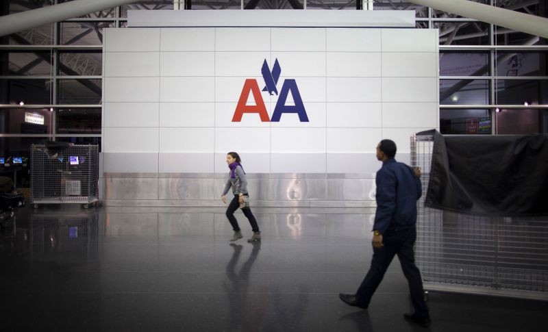 People walk past an American Airlines logo at John F.