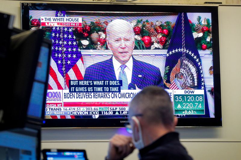 A trader works, as a screen displays President Biden delivering