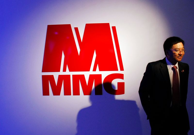 A man walks past the MMG Ltd logo after a