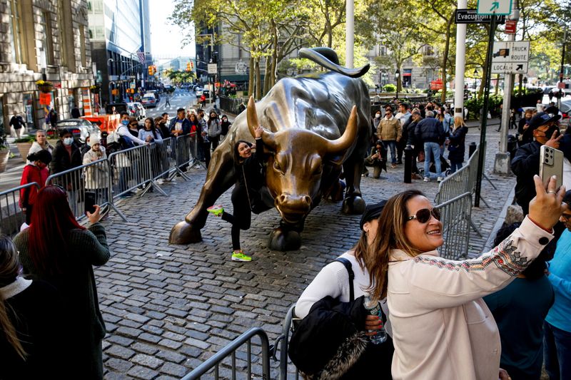Tourists gather around the Charging Bull statue, also known as