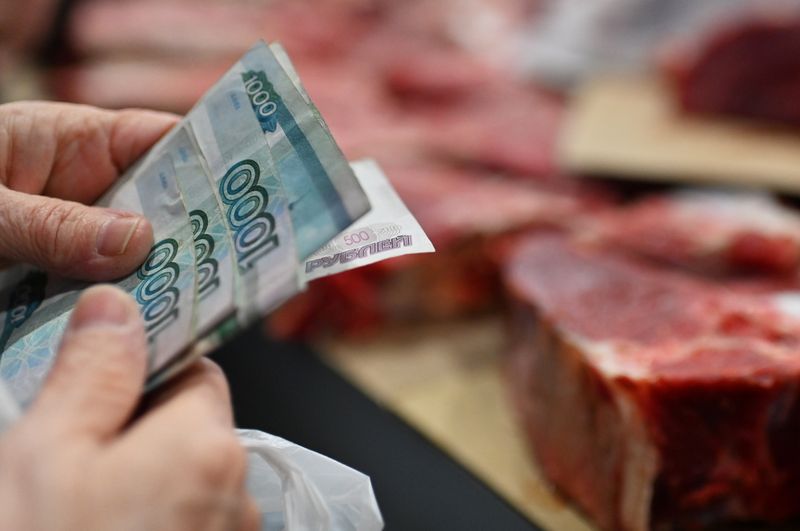A customer holds Russian rouble banknotes in a meat stall