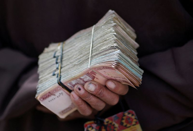 FILE PHOTO: Money changer holds a stack of Afghan currency