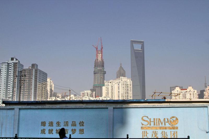 Man walks past a wall carrying the logo of Shimao