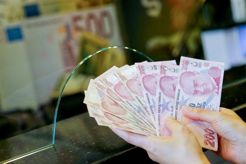 FILE PHOTO: A money changer holds Turkish lira banknotes at