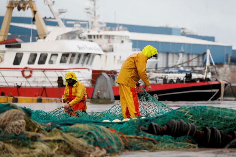 FILE PHOTO: French fishermen repair their nets at Boulogne-sur-Mer, northern