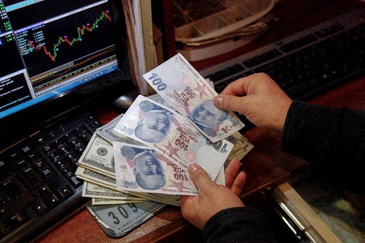 A money changer counts Turkish lira banknotes at a currency