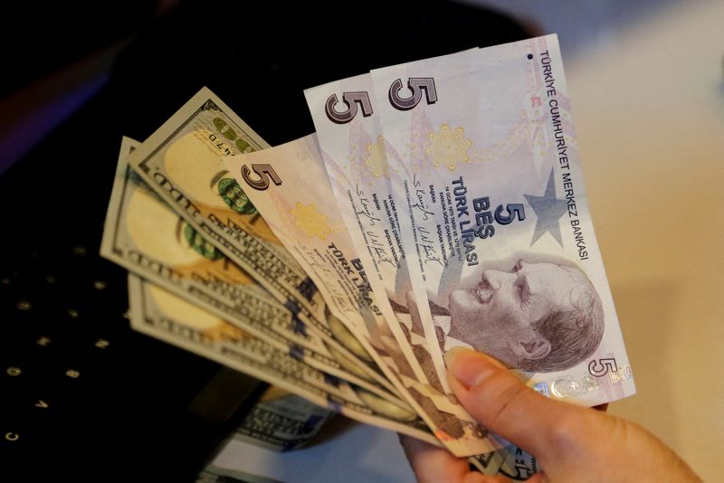 A money changer holds Turkish lira and U.S. dollar banknotes