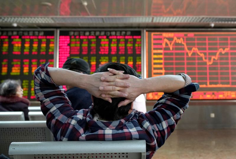 FILE PHOTO: An investor looks at a stock quotation board