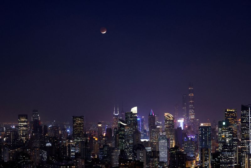 FILE PHOTO: Lunar eclipse rises over the skyline of Shanghai