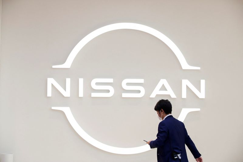 Man walks in front of the Nissan logo at Nissan