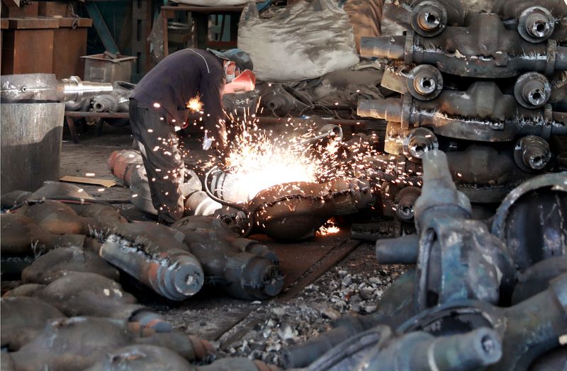 Worker welds automobile parts at a workshop manufacturing automobile accessories