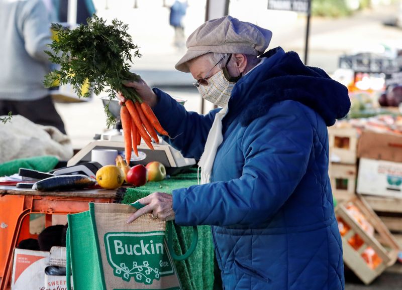 A lady buys carrots from a market stall in Buckingham,