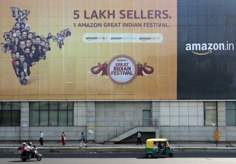 FILE PHOTO: People move past a hoarding of Amazon India