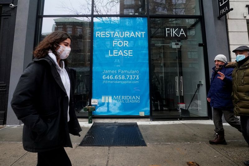 People walk past a shuttered restaurant in New York