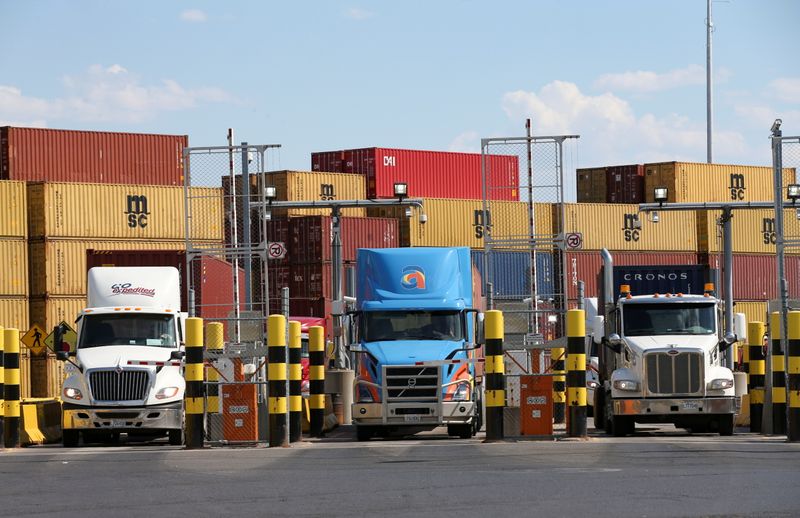 FILE PHOTO: Trucks loaded with shipping containers leave the Port