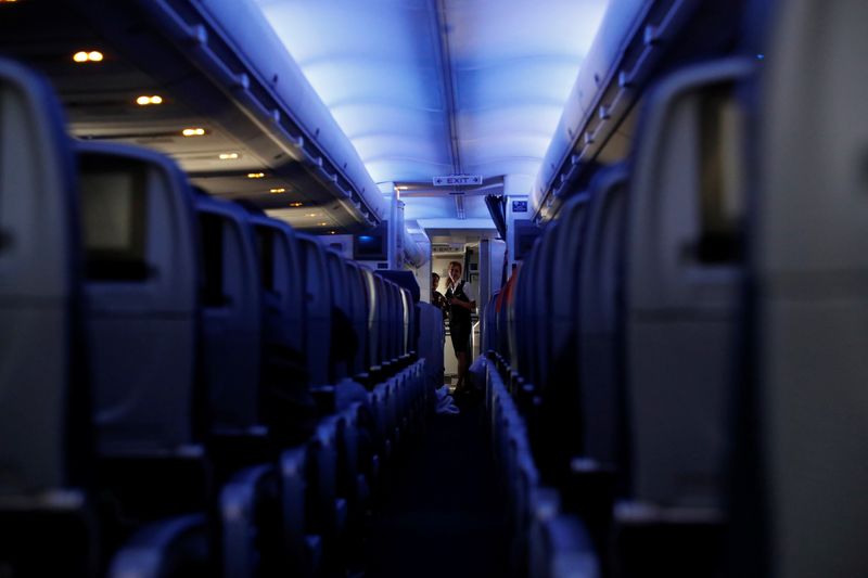 Flight attendants stand at the end of rows of empty