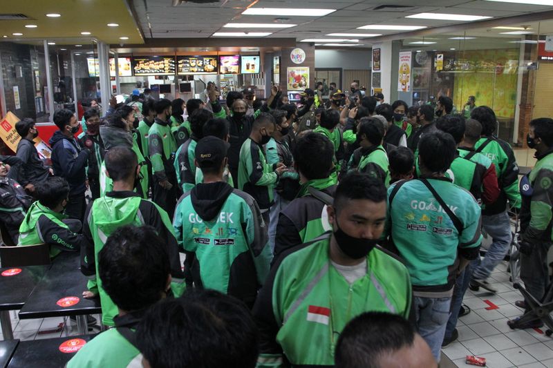 Food delivery drivers crowd in a McDonald’s restaurant as they