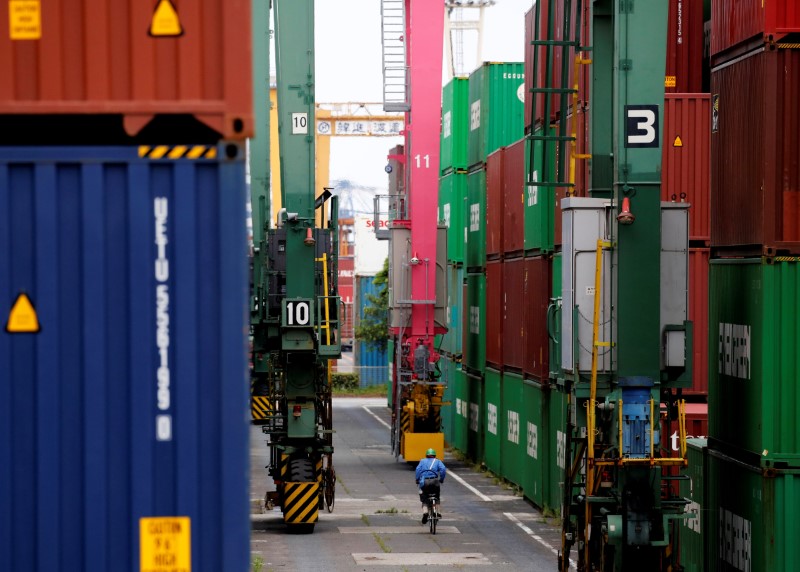 A man in a bicycle drives past containers at an