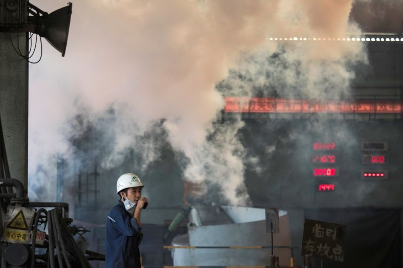 FILE PHOTO: Worker stands near smoke from blast furnace at