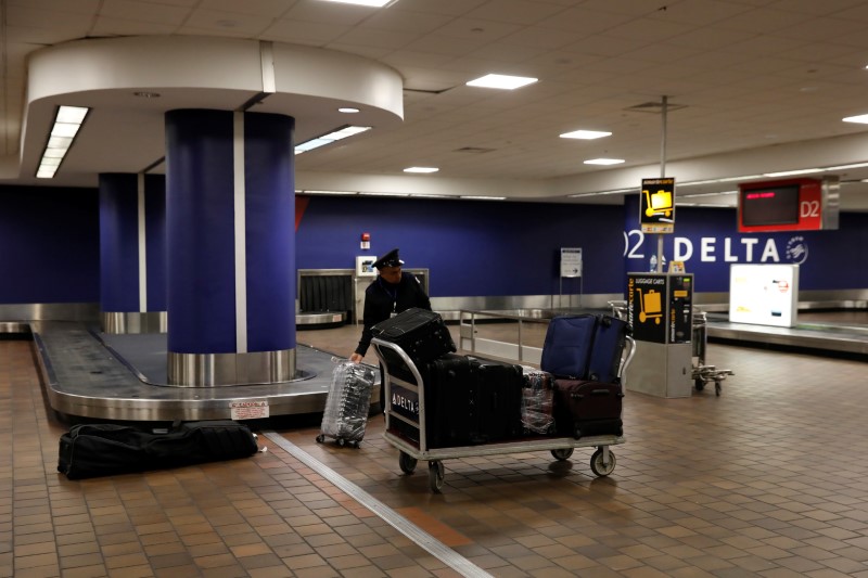 A baggage claim employee grabs bags from an empty baggage