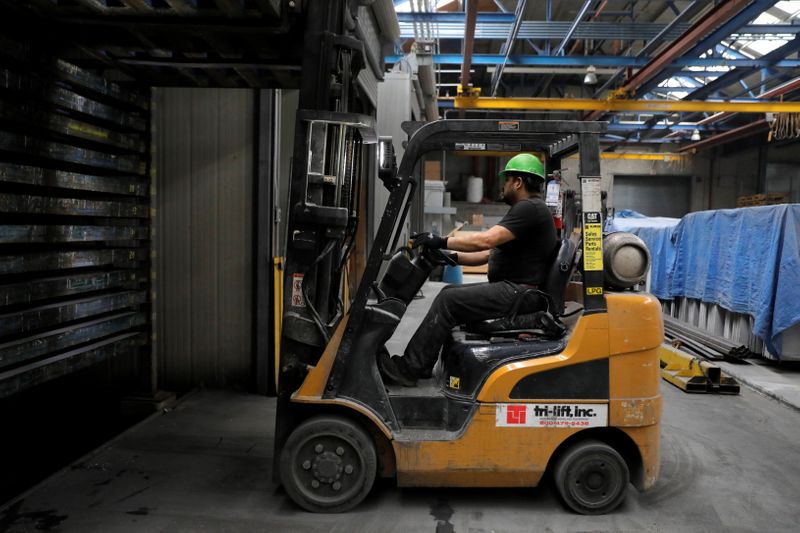 A worker in a forklift lifts a fresh slab in