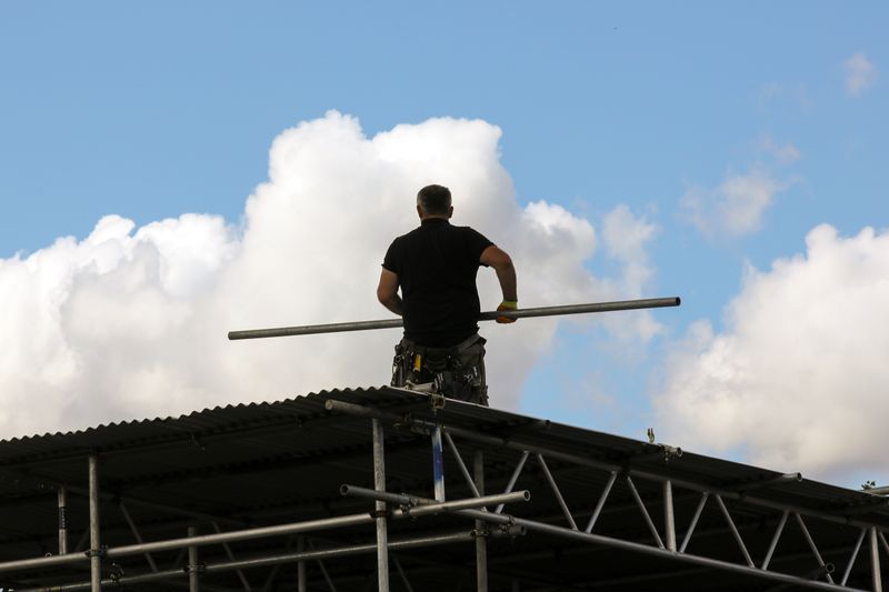 A construction worker carries a scaffold pole on the roof