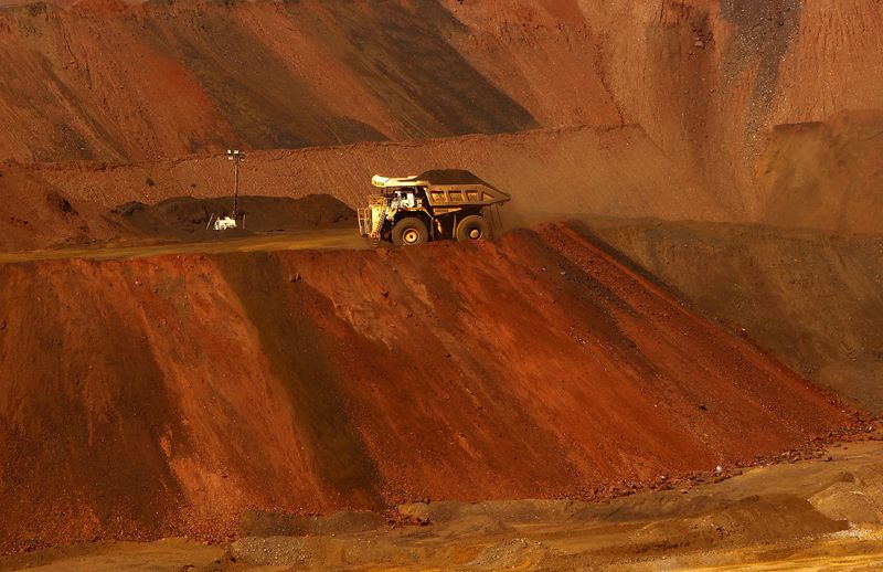 A truck carrying iron ore moves along a road at