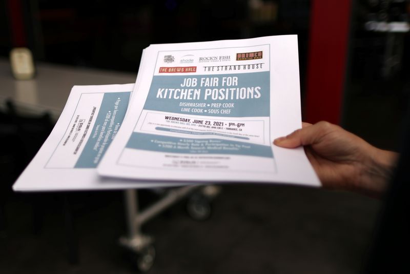 A woman holds fliers for a job fair for restaurant
