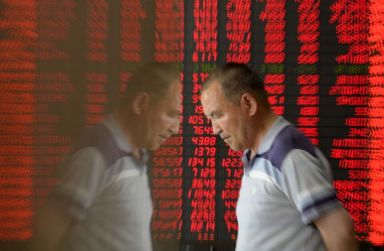 FILE PHOTO: An investor is reflected on the surface of