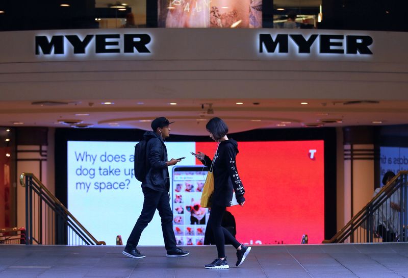 Shoppers use their phones as they walk past the entrance
