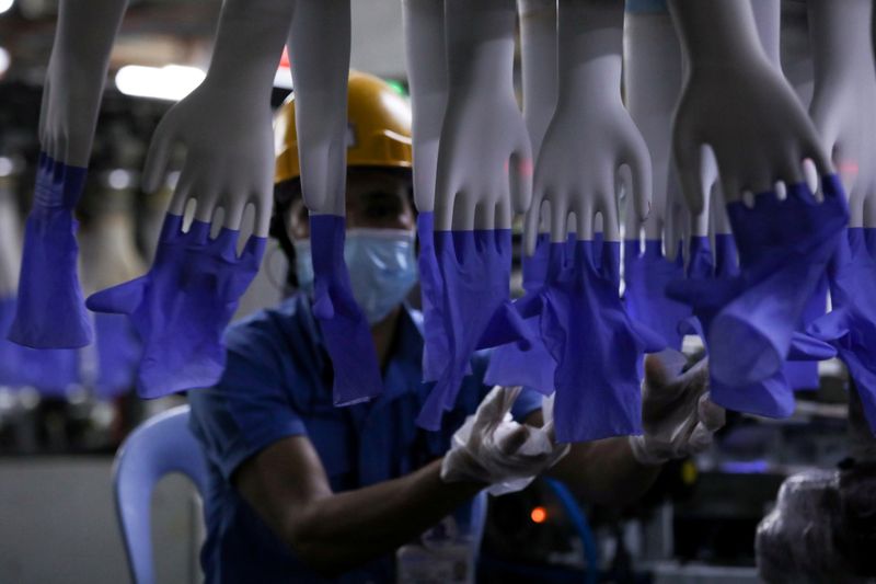 FILE PHOTO: A worker inspects newly-made gloves at Top Glove