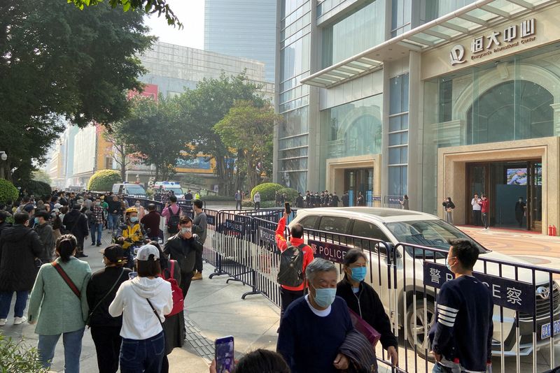 Protesters and police officers outside the Evergrande International Center in