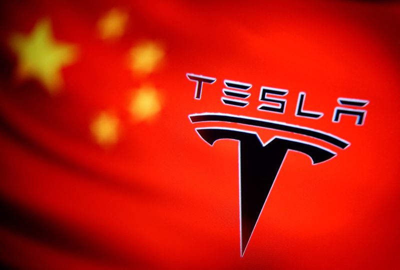 Chinese flag and Tesla logo is seen through a magnifier
