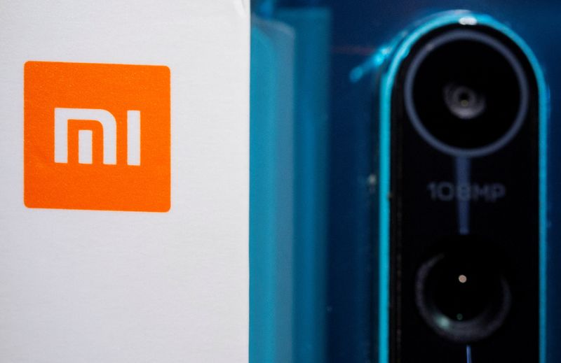 Xiaomi logo is seen next to a smartphone of the