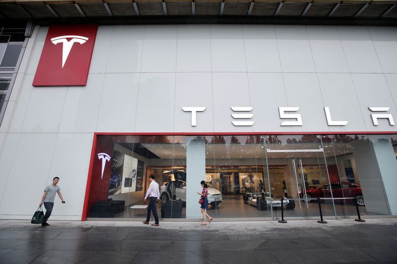 People walk past a showroom outside Tesla China headquarters in