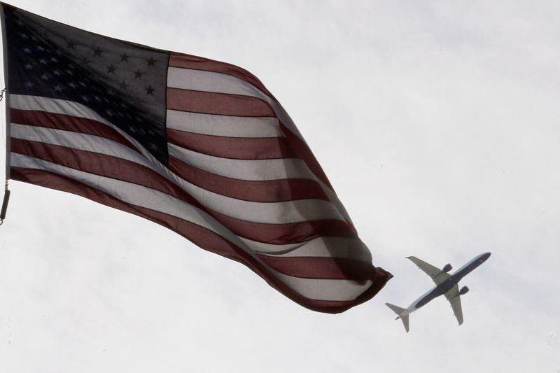 A Delta Airlines flight takes off past a U.S. flag