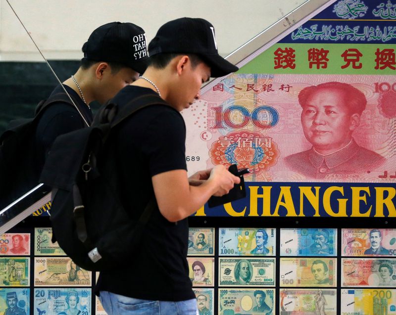 A man passes a money changer displaying a poster of