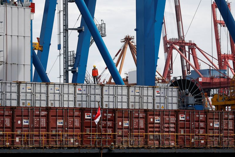 A worker stands on a container at Tanjung Priok Port