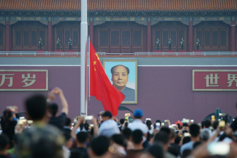 Visitors watch a flag-raising ceremony at Tiananmen Square, on the