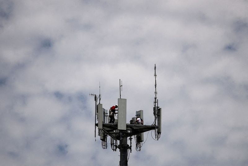 FILE PHOTO: Workers install 5G telecommunications equipment on a T-Mobile